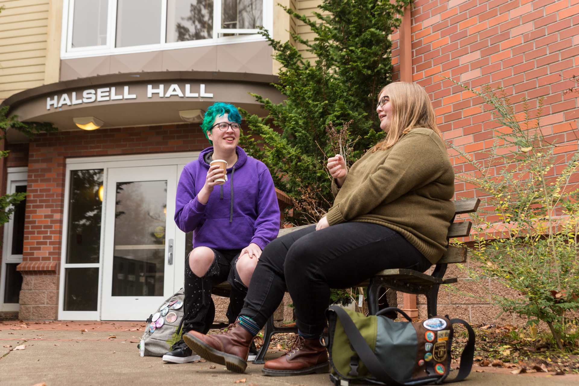 Two students talking to each other in front of Halsell Hall.