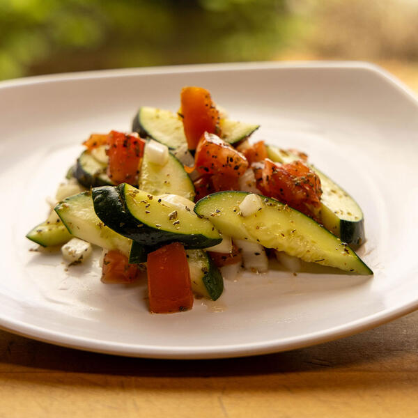 A plate of freshly made cucumber salad resting on a table in warm light