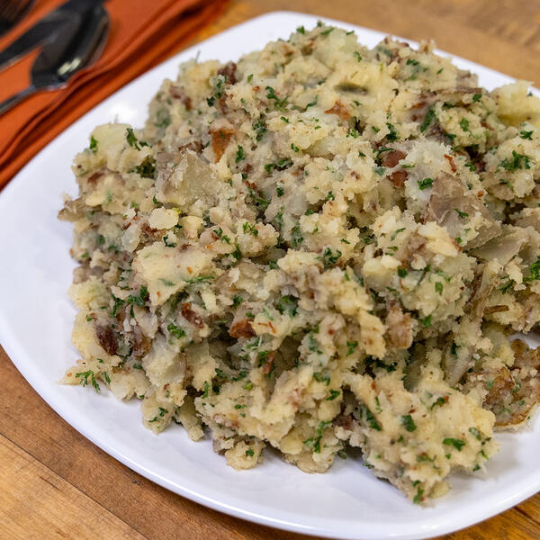A plate of warm potato salad garnished with herbs.