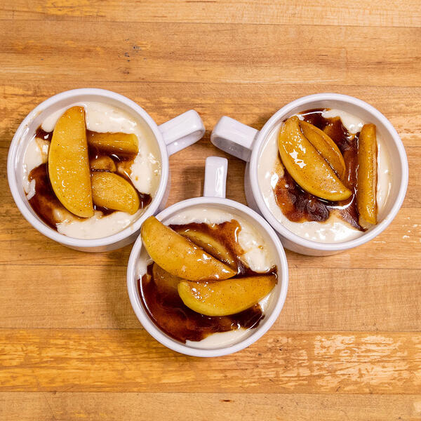 Three cups filled with rice pudding and topped with a caramel apple compote.